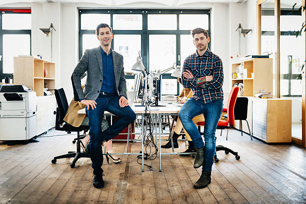 Two start-up business man sitting on desks in bright office loft.