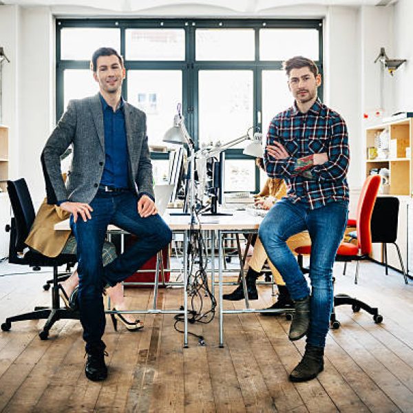 Two start-up business man sitting on desks in bright office loft.