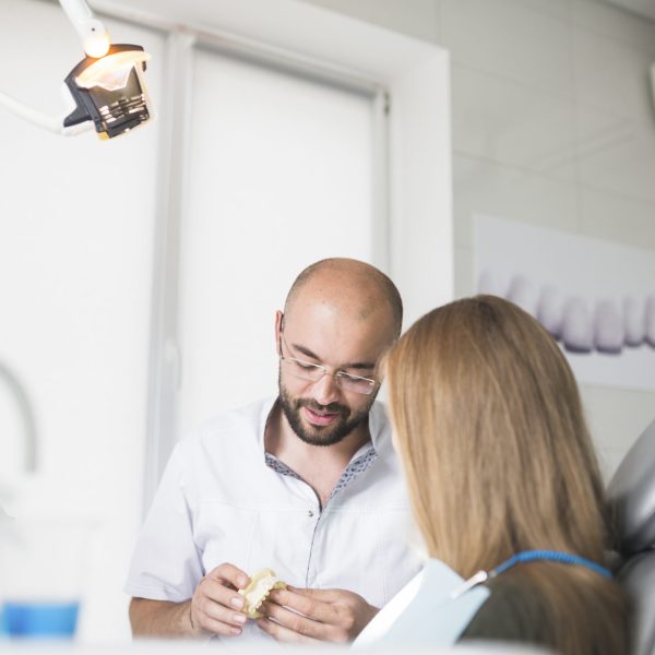 female-patient-front-male-dentist-holding-dental-jaw