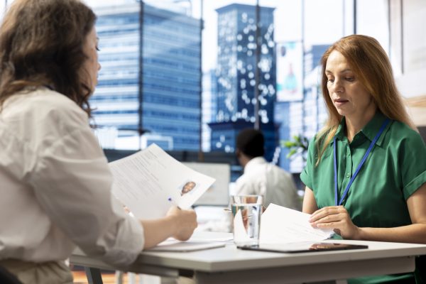 HR department worker negotiating job offers and salary packages with candidate after successful interview. Employer in workplace analyzing applicant resume, cover letter and background information