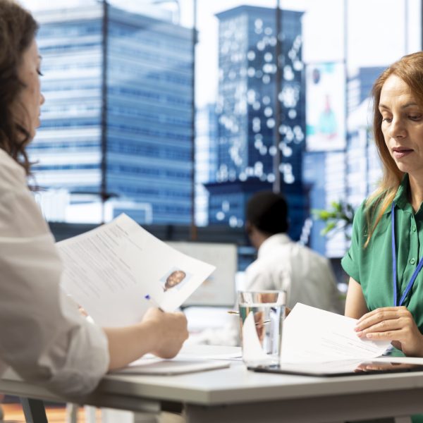 HR department worker negotiating job offers and salary packages with candidate after successful interview. Employer in workplace analyzing applicant resume, cover letter and background information