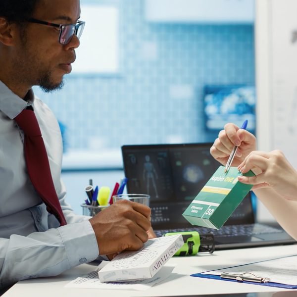 Physician recommending vitamins and painkillers on healthcare insurance, writing a stamped prescription document with instructions and the dosage of medication. Modern healthcare services. Camera A.