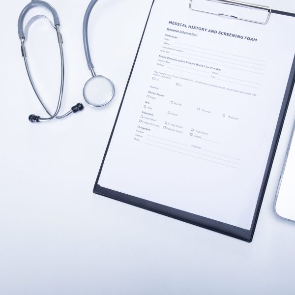 The top view of doctor desktop with stethoscope, clipboard with medical records form and computer laptop